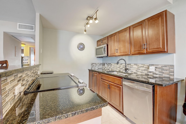 kitchen with backsplash, light tile floors, appliances with stainless steel finishes, and track lighting