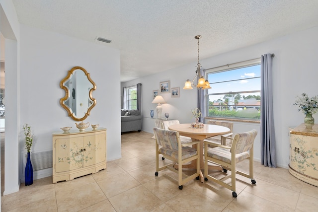 dining area featuring a notable chandelier, a textured ceiling, and light tile flooring