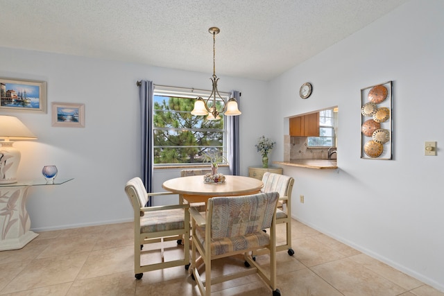 dining area with an inviting chandelier, a textured ceiling, and light tile flooring