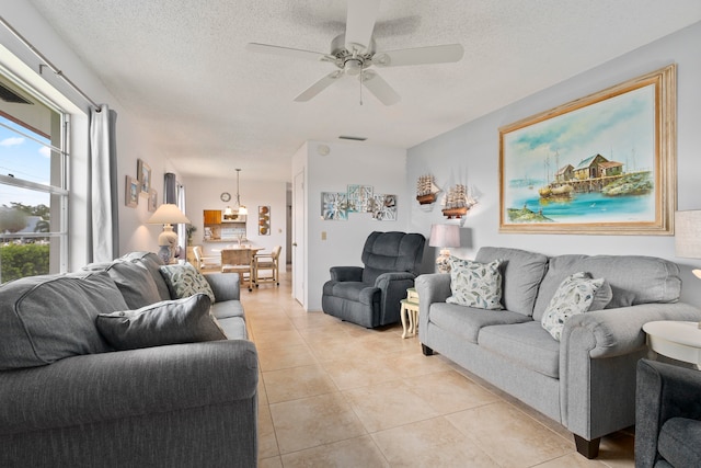 tiled living room featuring a textured ceiling and ceiling fan with notable chandelier