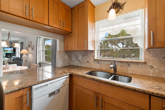 kitchen with sink, hanging light fixtures, dishwasher, backsplash, and light stone countertops