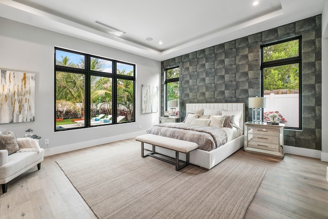 bedroom featuring light hardwood / wood-style floors and a raised ceiling