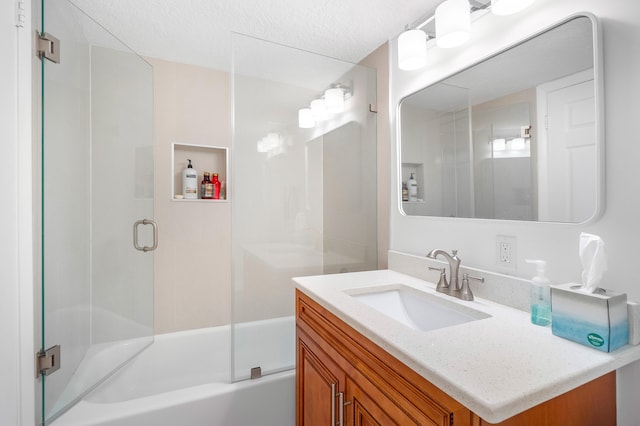 bathroom featuring a textured ceiling, vanity, and bath / shower combo with glass door