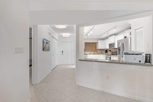 kitchen featuring tasteful backsplash, stainless steel appliances, white cabinets, and dark stone counters