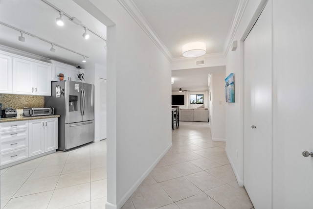 hall with light tile flooring, crown molding, and track lighting