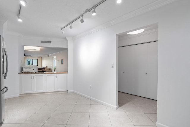 tiled empty room featuring a textured ceiling, rail lighting, and crown molding