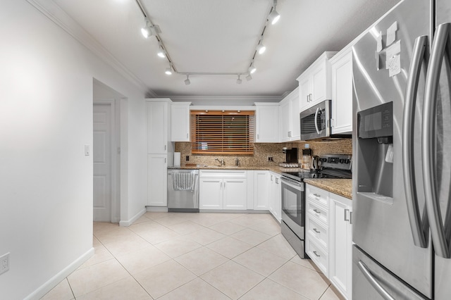 kitchen featuring backsplash, stainless steel appliances, white cabinets, rail lighting, and light stone counters