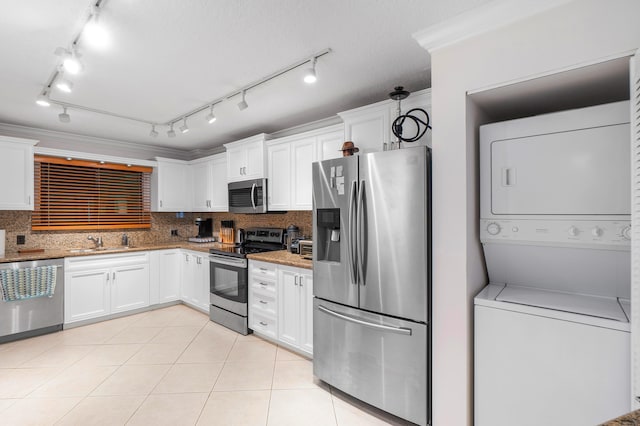 kitchen featuring tasteful backsplash, stacked washer / dryer, white cabinets, and appliances with stainless steel finishes