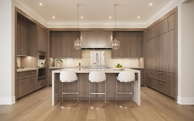 kitchen featuring wall chimney exhaust hood, dark brown cabinets, backsplash, light hardwood / wood-style floors, and hanging light fixtures