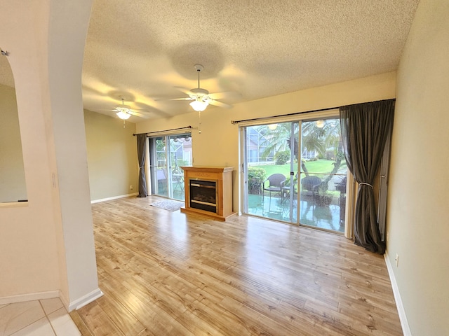 unfurnished living room featuring light hardwood / wood-style floors, ceiling fan, and a textured ceiling