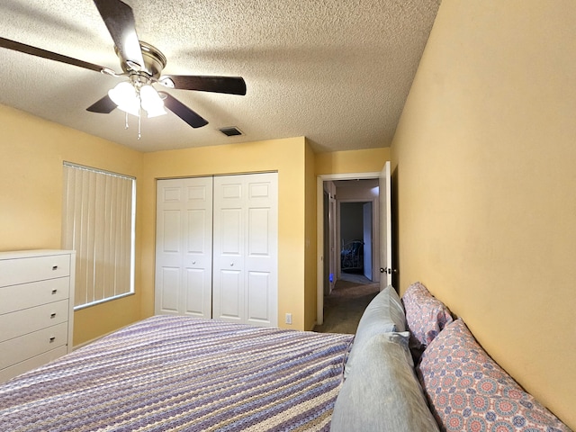 bedroom with a closet, a textured ceiling, dark carpet, and ceiling fan