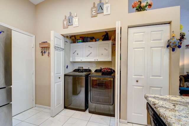 kitchen with light tile floors, white cabinetry, stainless steel fridge, and independent washer and dryer