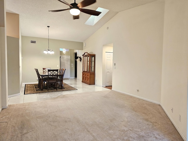 living room with light carpet, a skylight, high vaulted ceiling, and ceiling fan with notable chandelier