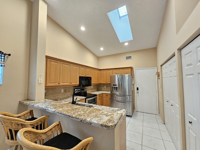 kitchen featuring kitchen peninsula, sink, a skylight, stainless steel appliances, and tasteful backsplash