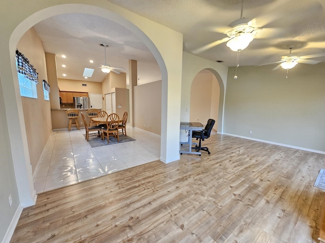 interior space with a textured ceiling, ceiling fan, and light wood-type flooring