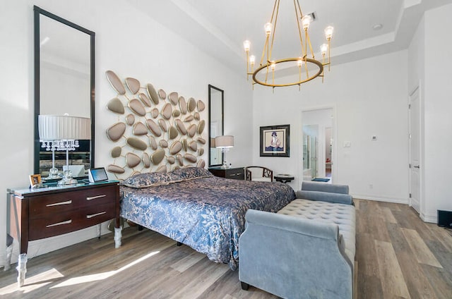 bedroom with a chandelier, light hardwood / wood-style floors, and a tray ceiling