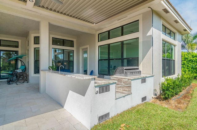 view of exterior entry featuring an outdoor kitchen and a patio