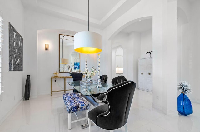 dining room featuring a raised ceiling and light tile flooring