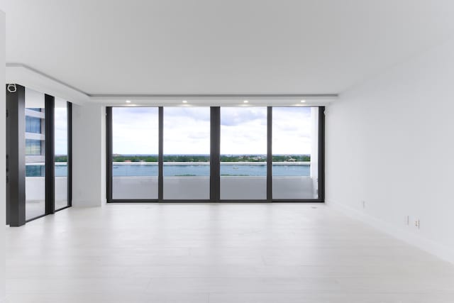 unfurnished room featuring a water view and a wall of windows