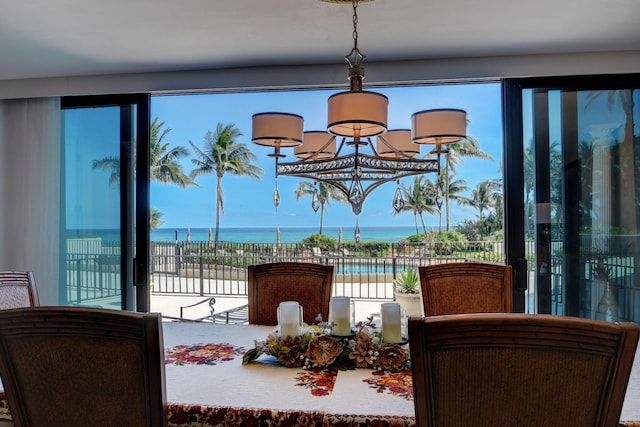 dining area with an inviting chandelier, a view of the beach, and a water view