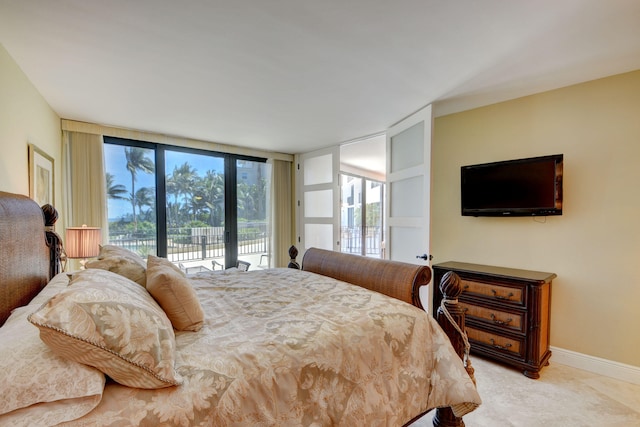 bedroom with a wall of windows, access to outside, and baseboards