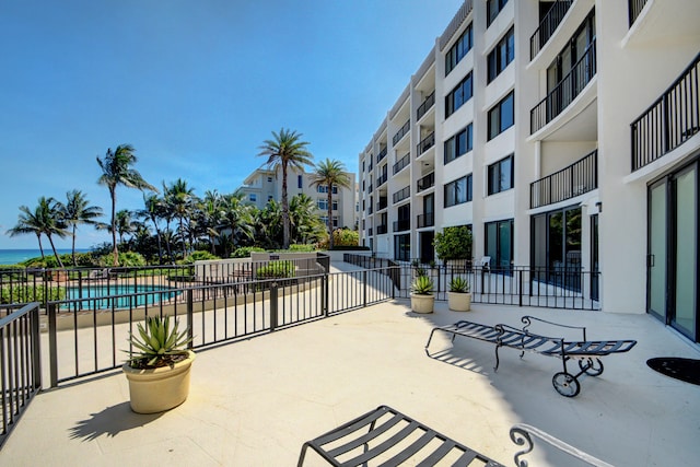 view of patio featuring a balcony and a community pool