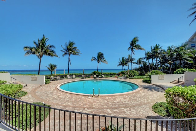 pool featuring a water view and a patio area