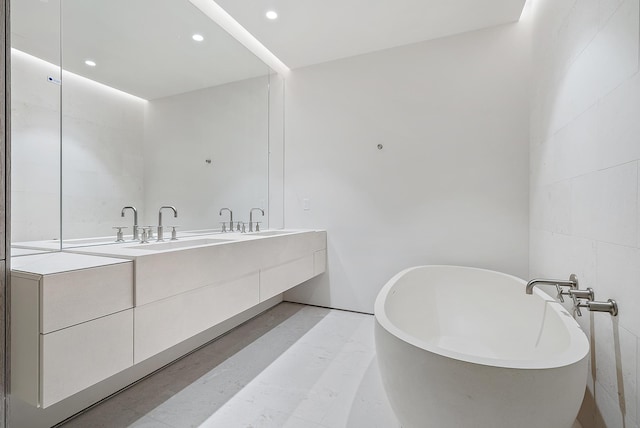 bathroom featuring double sink vanity, tile flooring, a bathing tub, and tile walls