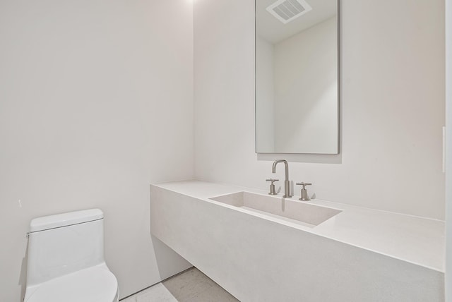 bathroom featuring toilet, sink, and tile flooring