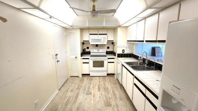 kitchen featuring white appliances, ceiling fan, sink, white cabinets, and light hardwood / wood-style floors