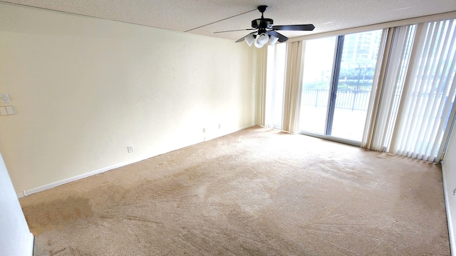 empty room with ceiling fan, floor to ceiling windows, light colored carpet, and a textured ceiling