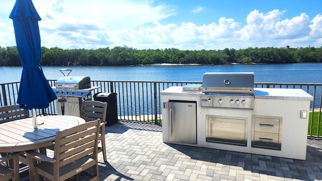 view of patio with an outdoor kitchen, a grill, and a water view