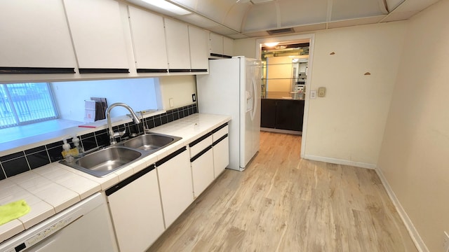 kitchen featuring tile counters, sink, light hardwood / wood-style flooring, white appliances, and white cabinets