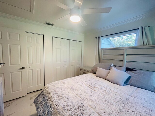 bedroom featuring multiple closets, crown molding, ceiling fan, and light tile flooring