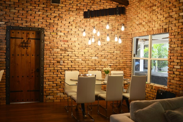 dining area featuring brick wall and dark hardwood / wood-style flooring