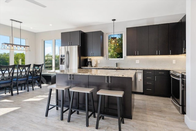 kitchen with a kitchen breakfast bar, a center island, decorative light fixtures, and appliances with stainless steel finishes