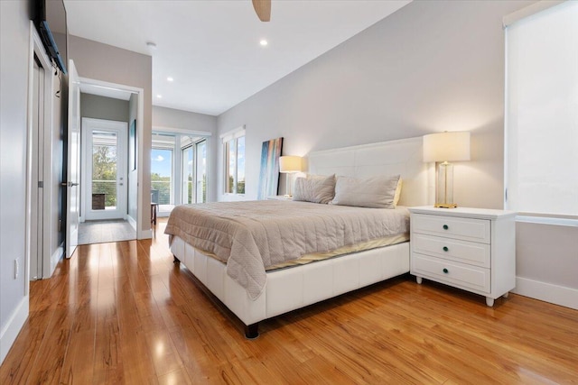 bedroom featuring ceiling fan, a barn door, access to exterior, and light wood-type flooring