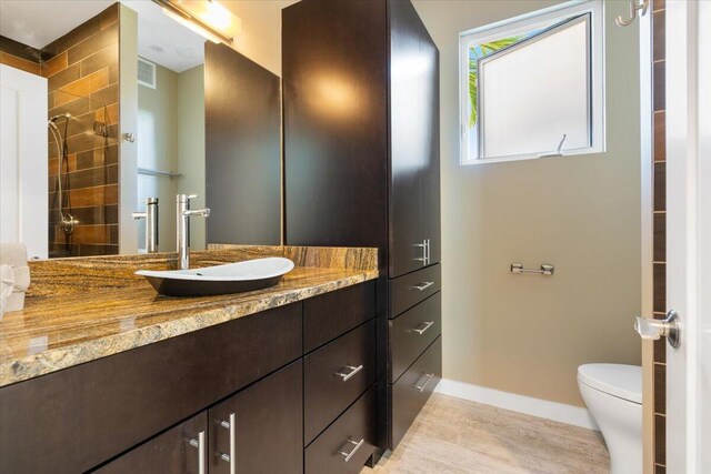 bathroom with walk in shower, vanity, and toilet