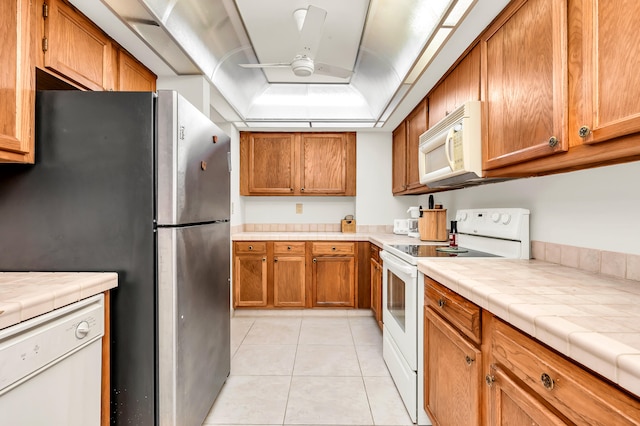 kitchen featuring light tile patterned floors, tile counters, ceiling fan, and white appliances