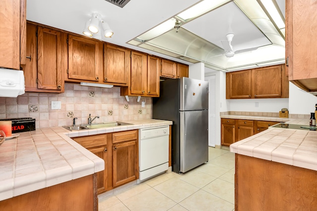 kitchen with tile counters, stainless steel refrigerator, dishwasher, ceiling fan, and decorative backsplash