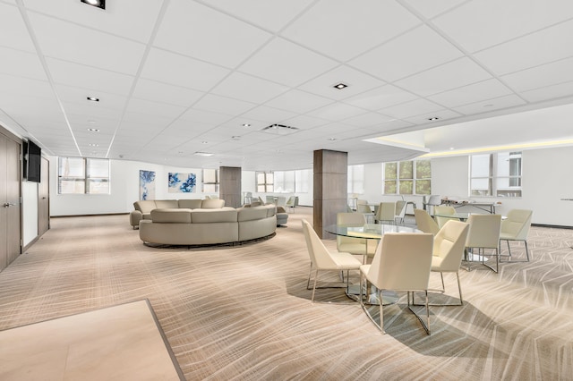 carpeted dining space with a drop ceiling