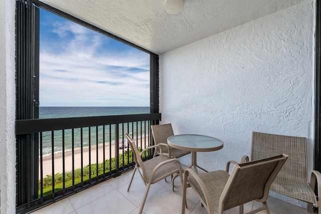 balcony with a water view and a view of the beach