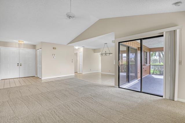 unfurnished living room featuring a textured ceiling, light carpet, and lofted ceiling