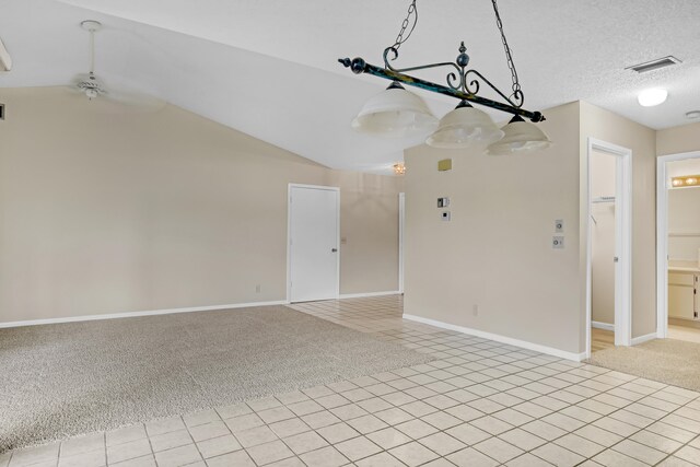 empty room featuring light carpet, a textured ceiling, vaulted ceiling, and ceiling fan