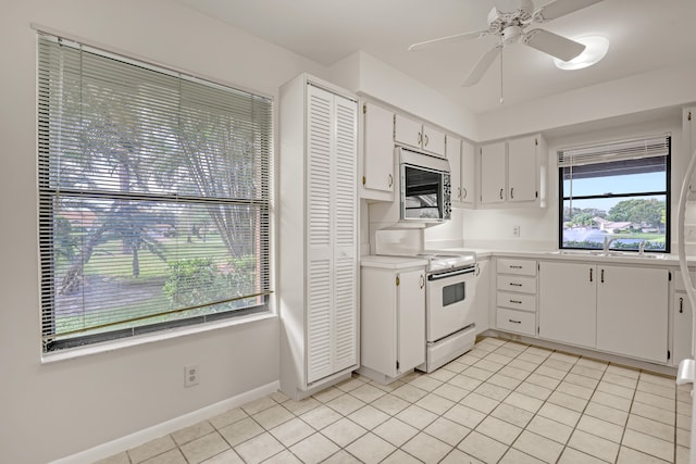 kitchen featuring sink, ceiling fan, light tile patterned floors, white range with electric stovetop, and white cabinetry