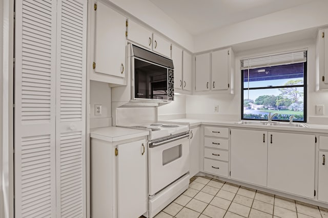 kitchen with electric range, light tile patterned flooring, white cabinetry, and sink