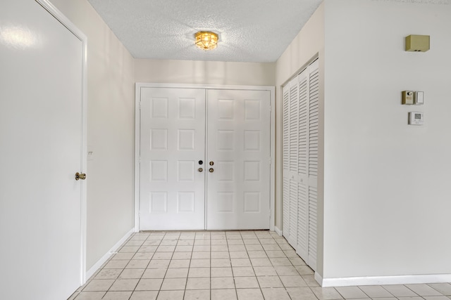 entryway featuring light tile patterned floors and a textured ceiling