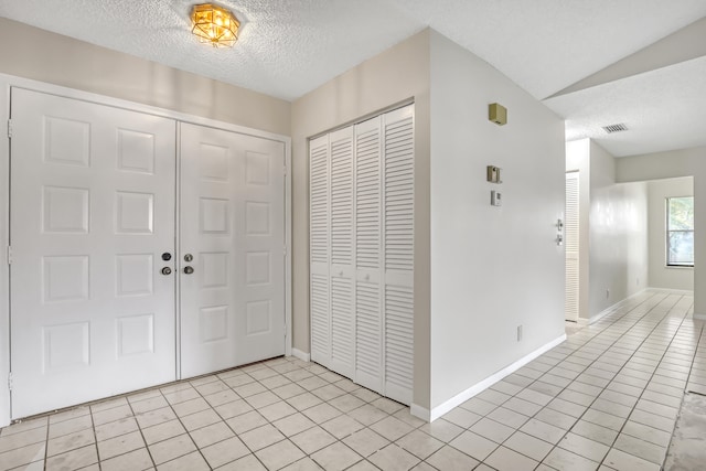 tiled entrance foyer with lofted ceiling and a textured ceiling