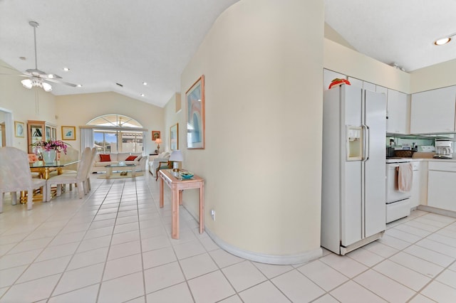 kitchen with electric range, lofted ceiling, white fridge with ice dispenser, white cabinetry, and light tile patterned flooring