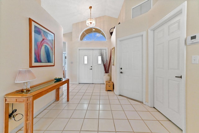 entrance foyer featuring light tile patterned floors, vaulted ceiling, a chandelier, and visible vents